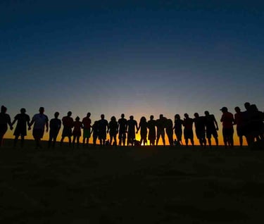people who are united standing on the beach in front of the rising sun