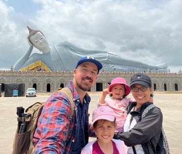 a family posing for a photo in front of a large statue of a buddha statue