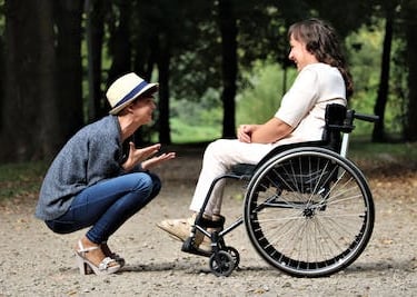 a woman in a wheelchair is talking to a man in a wheelchair