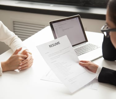 a woman in a white suit and glasses sitting at a desk