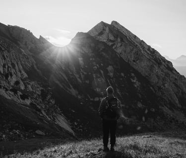 Persona che osserva l’alba tra le montagne, simbolo di introspezione, crescita personale e cammino v