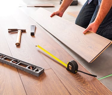Hardwood flooring installer professionally installing plank flooring.