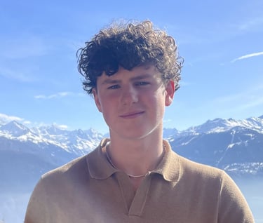 a young man in a brown shirt with snowy mountains in background