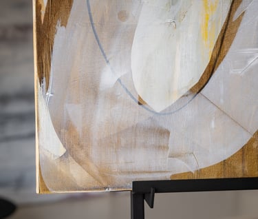 Abstract painting with textured brushstrokes of white, gold, and grey on a canvas.