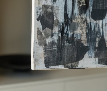Close-up of a modern abstract canvas painting with black and grey brushstrokes on a textured white background.