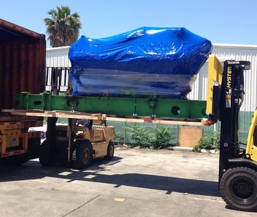 loading a large item with a large blue tarp into a truck