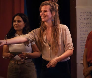 Female public speaking trainer, handing out note, smiling in corporate workshop setting.