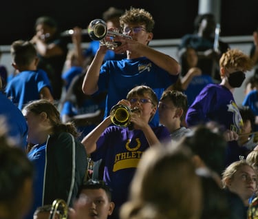 candid photograph of high school band member mentoring a middle school band member