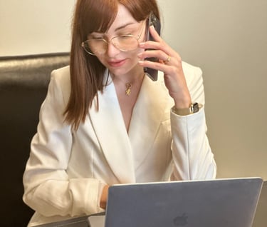 a woman in a white suit and glasses talking on a cell phone