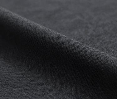 Close-up detail of high-quality fabric texture in dark charcoal #333333. The image emphasizes the craftsmanship and the intricate weave of the textile. Clean, minimalist aesthetic.