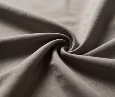 Macro shot of an artistic fabric texture with deep folds, illuminated by harsh, direct light creating dramatic contrast. Palette consists of #D5BFB3 and deep charcoal shadows #363131. High-end fine art photography style.