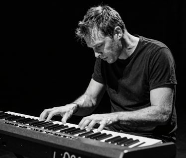 A dynamic shot of a keyboard player completely lost in the music. Elegant black and white photography, capturing raw emotion. Deep black background, off-white keys. Western European / Dutch concert.