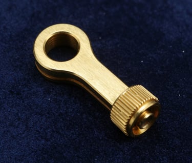 Macro photography of a custom-designed brass prop accessory sitting on a dark midnight blue velvet surface. The lighting is precise, highlighting the metallic sheen and meticulous craftsmanship. Western European luxury editorial style.