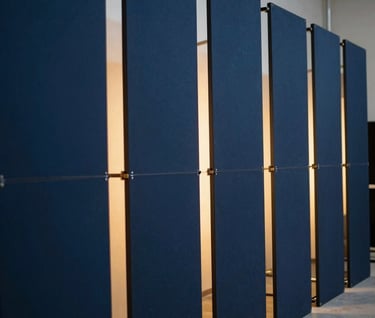 Perspective shot of a series of dark blue panels used in a film set, arranged to create depth. Golden light spilling through gaps. Professional set design photography, elegant and immersive mood.