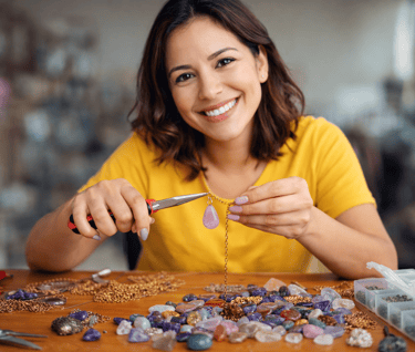 Mujer practicando bisutería con cuarzos y cadenas de oro.