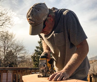 Brewer Construction carpenter using an impact driver on a wooden deck structure in Evergreen.