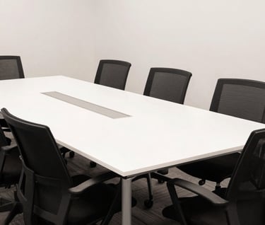 A wide shot of a professional North American / US creative agency meeting room with jet black chairs and a large white table, captured in clean, bright photography style.