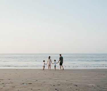 A wide shot of a family playing on a secluded Bali beach at dawn. The atmosphere is airy and minimalist, with soft blues and sandy tones matching #F8F4F0. Natural, unposed movement.