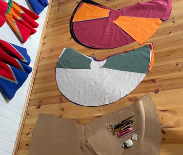 Handmade colorful fabric patterns and sewing tools laid on a wooden floor in a clothing design studio.
