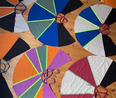 Handmade colorful circular capes with neon trim. 