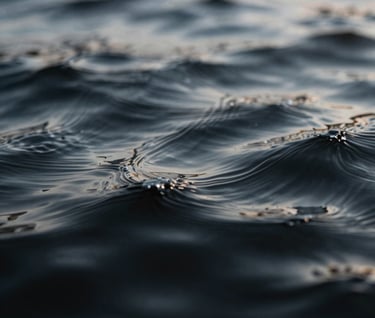 Macro photography of ripples in dark water, capturing a liquid texture that looks like brushed metal. The lighting highlights the peaks in #D0D5DB against deep #0A0A0C shadows.