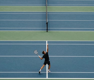 A wide shot of a modern tennis court with a rhythmic geometric pattern of dark blue and white lines. An athlete in black apparel is caught in a powerful serve. Bright, professional lighting, Western / International.