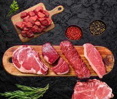 Bœuf halal cru : steaks et morceaux variés sur planche avec épices et herbes fraîches.