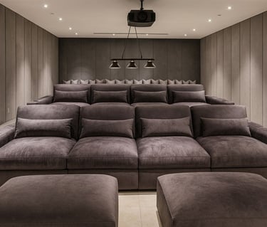 Private home theater with tiered dark gray velvet chaise lounges, custom wall panels, and modern lighting by Solo Home Decor.