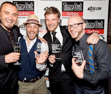a group of men standing around celebrating winning 3 awards at an event