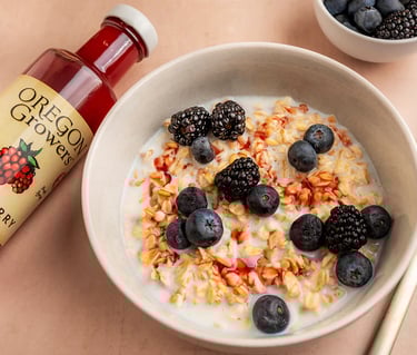a bowl of cereal with berries and a bottle of syrup