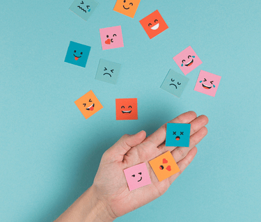 image d'une main tenant des papiers avec des visages d'émotions