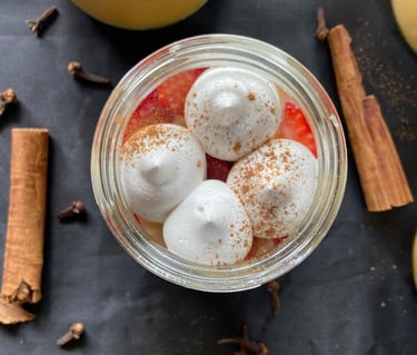Dessert jar plated with meringue dots, strawberries and cinnamon as background