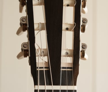 Close-up of a classical guitar headstock with nylon strings and tuning pegs.