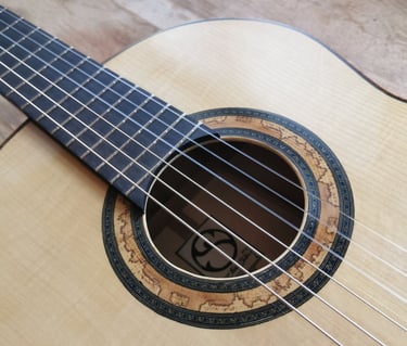 Close-up of a handcrafted classical guitar showing the soundhole rosette and spruce top.