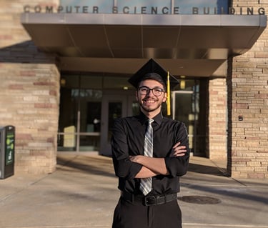 2014, recently graduated Luis posing in front of his Computer Science department.