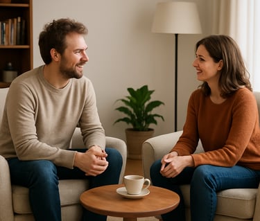 A smiling couple having a conversation over coffee in a cozy living room with neutral decor.