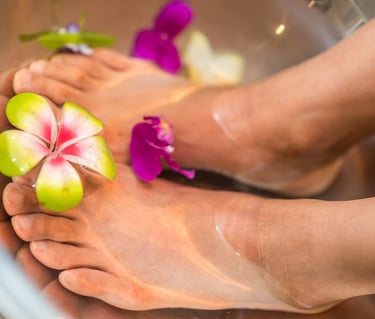 Feet bathing in a bowl of water with flowers