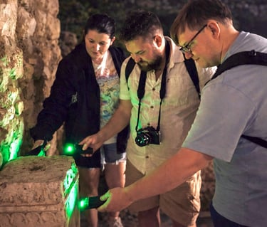 Tour participants examining ancient stone ruins with green UV lights during Athens Ghost Tour