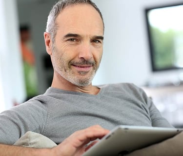 a man sitting on a couch with a tablet computer Martin PE / COACH