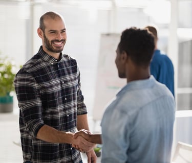 A smiling businessman shaking hands with a colleague in a bright office setting.