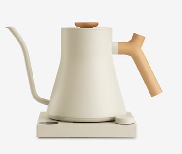Off-white electric gooseneck kettle with wooden handle on a matching minimalist heating base.