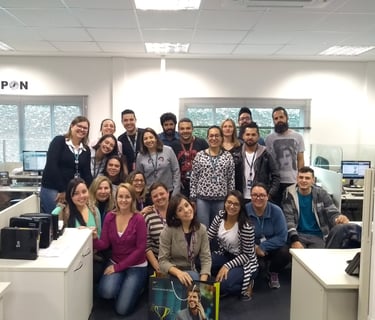 uma equipe de trabalho, um grupo de pessoas em pé ao redor de uma mesa posando para uma foto
