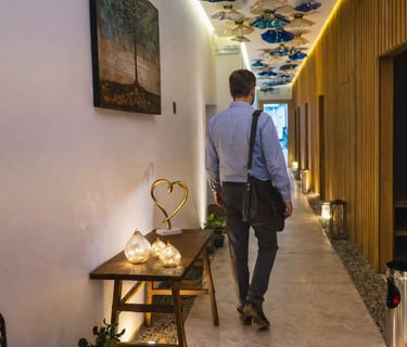 a man walking down a hallway with a table and chairs