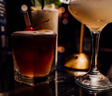 a table with a glass of alcohol and a cocktail