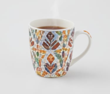 A high-quality ceramic mug decorated with a complex, colorful botanical pattern in warm and cool shades.