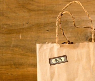 Brown paper shopping bag with J & D Ochoa Woodworking Logo sticker