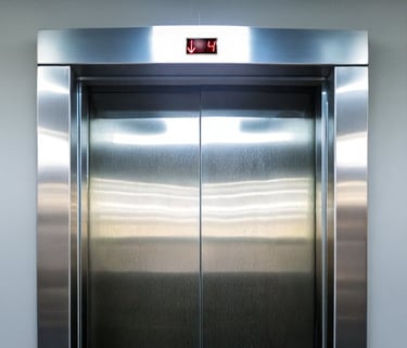hallway elevator door and surrounding frame cladded in stainless steel