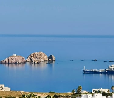 Sea scape of Paros looking to the sea, small rocky islands and a comertial vesel