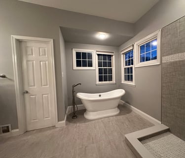 Wide view of renovated bathroom with freestanding bathtub and tiled shower wall