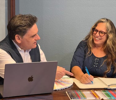 a man and woman sitting at a table with a laptop